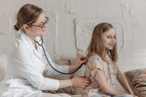 Pediatrician examining a smiling young girl.